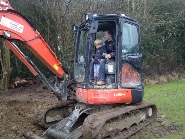 Trevor Tack in his digger, with little helper at Spiritual Garden